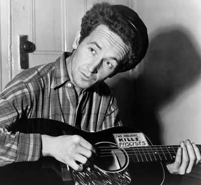 American folk singer Woody Guthrie in 1943; at the height of World War II his sign reads, This Machine Kills Fascists." (Al Aumiller/New York World-Telegram and The Sun)